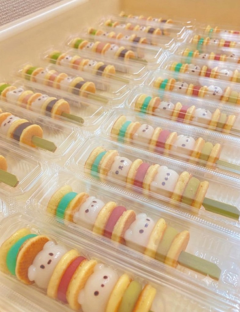透明パックに入った、くまの顔をあしらった色とりどりの串状菓子が多数並ぶ様子