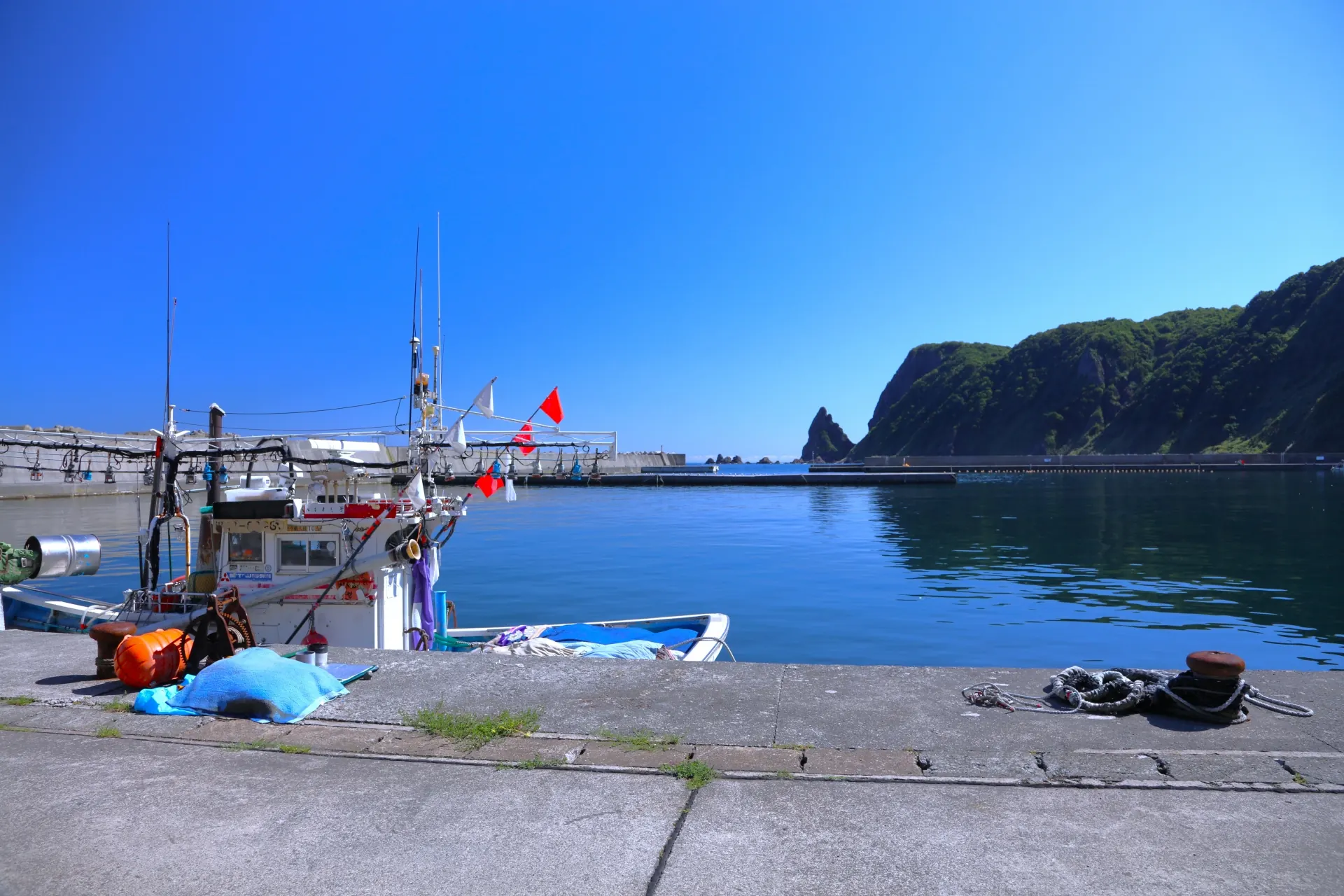 漁船と青い海、岩山が見える北海道の漁港