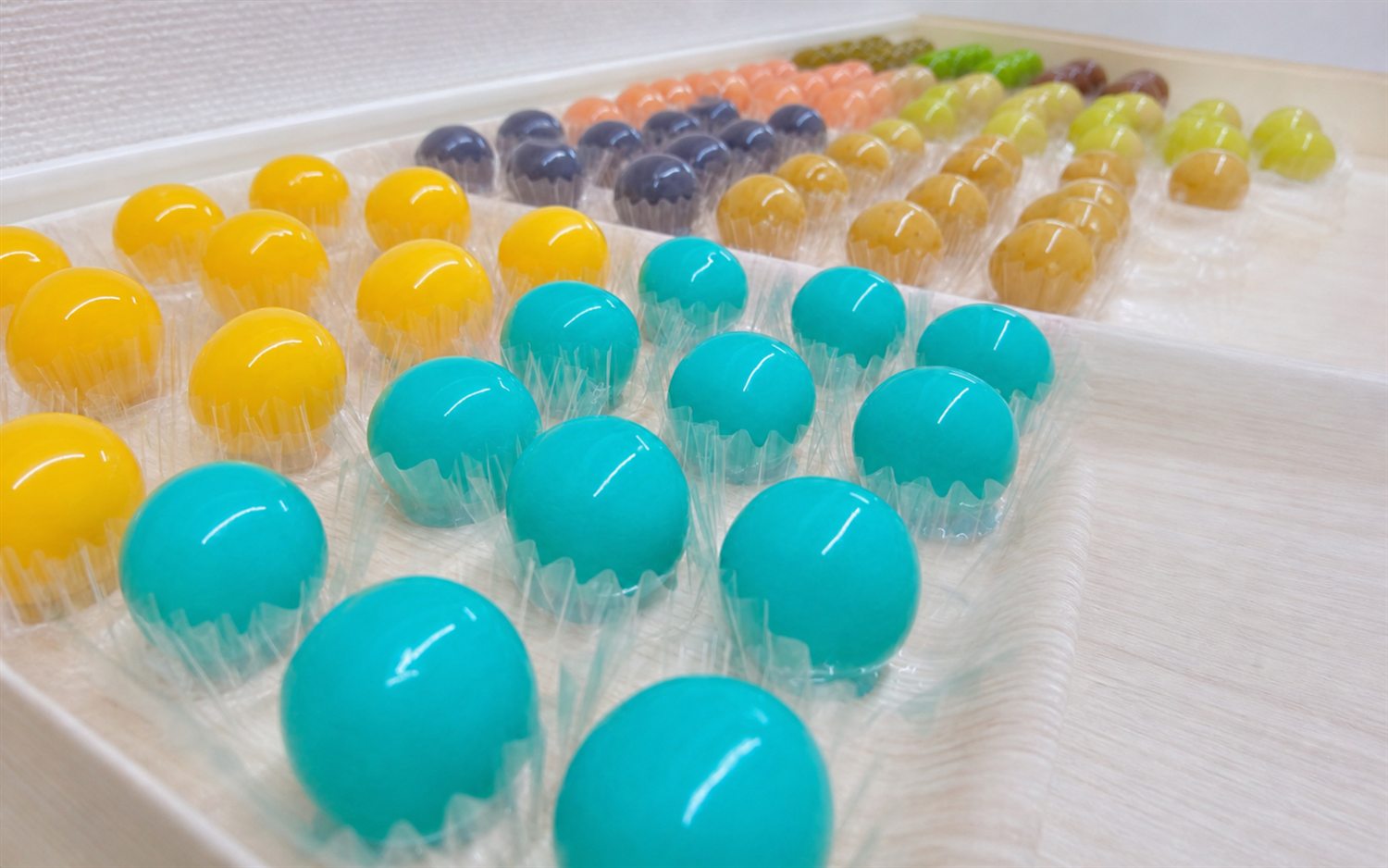 色とりどりの丸い菓子が並ぶ製造風景の試作用ビジュアル